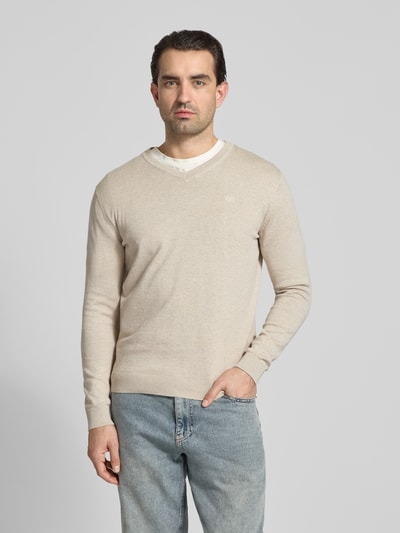 Mannelijk model draagt Regular Fit Pullover aus reiner Baumwolle van Tom Tailor in effen beige, fijngebreide katoen, V-hals, logostiksel, lange mouwen, geribde boord en manchetten, voorkant volledige lichaamsweergave.