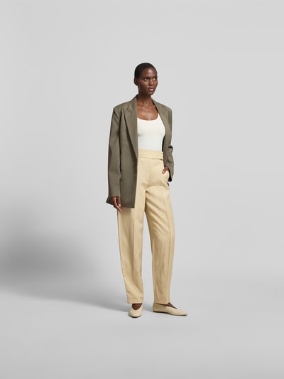 Frauenmodel trägt Wide Fit Stoffhose aus Viskose-Mix von Joseph in Beige mit Bügelfalten und Gesäßtaschen, Ganzkörperansicht von vorne.