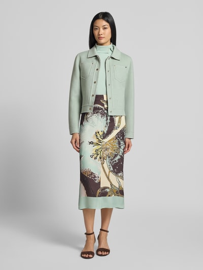 Frauenmodel trägt Jacke mit Knopfleiste und Brusttaschen von Marc Cain in hellem Mintgrün aus reiner Baumwolle, Regular Fit, Umlegekragen, Knopfleiste, Brusttaschen, kombiniert mit gemustertem Rock, Ganzkörperansicht von vorne. Rückenlänge 51 cm, Schulterbreite 41 cm, Brustweite 47 cm, Ärmellänge 61 cm bei Größe 36.