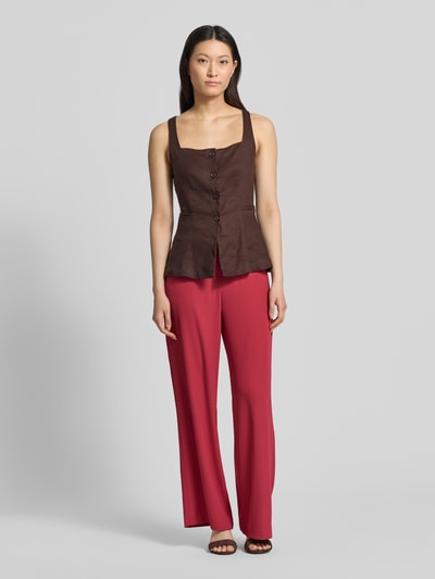 Modelka nosi spodnie materiałowe 'Stoffhose mit elastischem Bund und Eingrifftaschen' od kolekcja Jake*s Collection, mieszanka materiałów z dodatkiem streczu, krój wide leg fit, elastyczny pas, wpuszczane kieszenie, tylne dekoracyjne kieszenie z wypustkami, szerokość w rozmiarze 36: 38 cm, długość wewnętrzna nogawki w rozmiarze 36: 78 cm; całkowity widok z przodu.