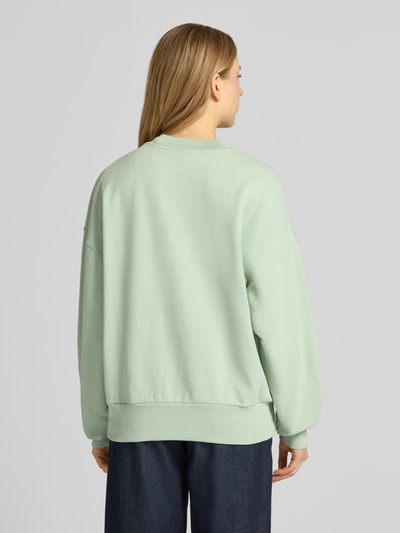 Kobiece modelka nosi Oversized Fit Sweatshirt aus reiner Bio-Baumwolle Modell 'ICONIC A ALIZAA' von Armedangels, kolor jednolity, długi rękaw, okrągły dekolt, naszywane logo, faktura dzianiny, materiał bio bawełna, widok całej sylwetki z tyłu.