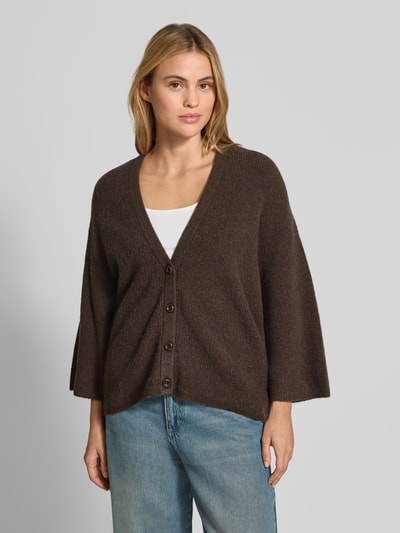 Kobiece modelka nosi kardigan z elastycznej mieszanki materiałów z bawełną, krój oversized fit, imitacja dzianiny, listwa guzikowa, dekolt w serek, długość tyłu 63 cm, długość rękawów 35 cm, Model 'DAMSVILLE' od American Vintage, widok całej sylwetki z przodu.
