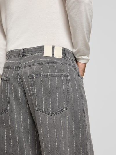 Männermodel trägt Wide Fit Jeans aus puur katoen van Wood Wood in grijs met witte strepen, 5-pocketmodel, knoop- en ritssluiting, detailaufnahme rug. Heren jeans, bandwijdte maat 32/32: 45 cm, binnenbeenlengte maat 32/32: 78 cm.