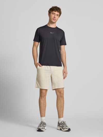 Männermodel trägt Herren T-Shirt mit Logo Modell 'DIVISION' von HALO, Material-Mix mit Stretch-Anteil, Regular-Fit, Rundhalsausschnitt, Rückenlänge Größe M 69 cm, dunkler Stoff, schlichte Optik, Ganzkörperansicht von vorne.