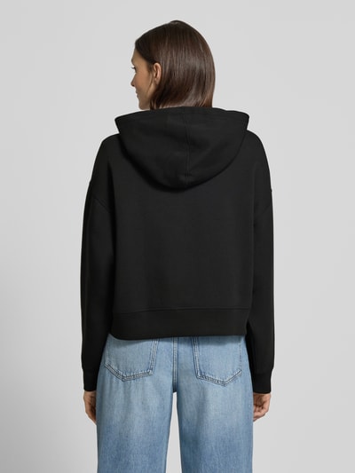 Frauenmodel trägt Oversized Hoodie aus Baumwoll-Mix von Lacoste Sport in Schwarz, unifarben, Kapuze, Rippbündchen, Ganzkörperansicht Rückansicht.