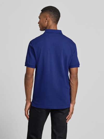 Männermodel trägt Regular Fit Poloshirt mit Logo-Stitching von Gant aus elastischem Baumwoll-Mix in Blau, Ganzkörperansicht Rückansicht.