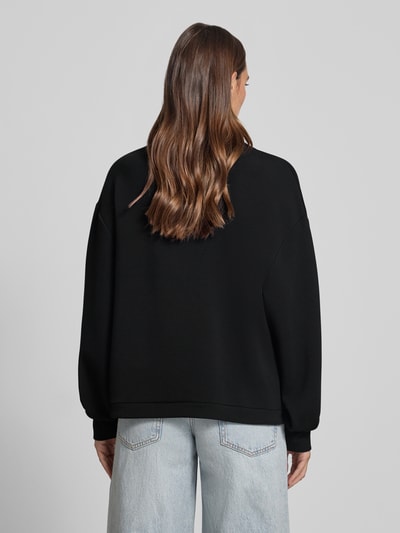 Männermodel trägt Regular Fit Sweatshirt aus mieszanka wiskozy Modell 'Betsy' von VARLEY, stójka, tunel w pasie, czarny, gładka faktura, Ganzkörperansicht Rückansicht.