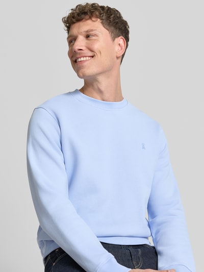 Männermodel trägt Regular Fit Sweatshirt aus reiner Bio-Baumwolle Modell 'BAARO LOOP' von Armedangels in Hellblau, Rundhals, Logo-Stitching, gerippte Ärmel und Saum, unifarben, Sweat-Material, Nahaufnahme Oberkörper.