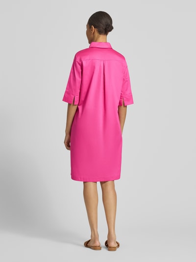 Frauenmodel trägt knielanges Hemdblusenkleid mit Eingrifftaschen von Christian Berg Woman aus pinker Baumwolle, gerade geschnitten, Rückansicht Ganzkörperansicht.
