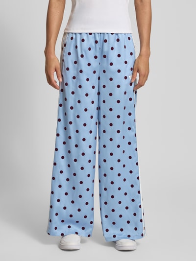 Frauenmodel trägt Loose Fit Sweatpants mit Polka Dots Modell 'CLESKY' von adidas Originals in Optik:Allover-Muster, Materialverarbeitung: Satin, Wide-Leg-Pants, Logo-Print, 3-Streifen, Bundabschluss: Tunnelzug, Ganzkörperansicht von vorne.