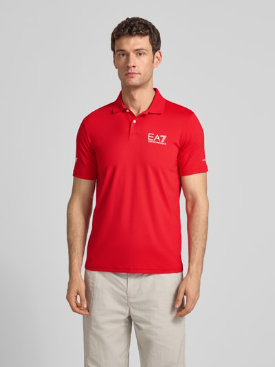 Männermodel trägt Regular Fit Poloshirt mit Logo von EA7 Emporio Armani in Rot, Polokragen, Logo, Stretch-Material, Ganzkörperansicht von vorne.