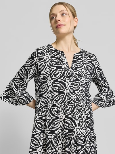 Frauenmodel trägt Minikleid mit Tunika-Ausschnitt von Christian Berg Woman Selection aus Reine Baumwolle, Schwarz-Weiß-Muster, taillierte Passform, Halbarm, Nahaufnahme Oberkörper. Rückenlänge bei Größe 36: 89 cm, Brustweite 41 cm, Ärmellänge 43 cm.