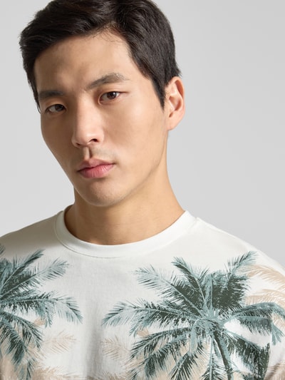 Męski model nosi Slim Fit T-Shirt mit floralem Allover-Print od Antony Morato, czysta bawełna, krój slim fit, okrągły dekolt, długość tyłu 69 cm w rozmiarze M, jasne kolory, motyw roślinny, zbliżenie na górną część ciała