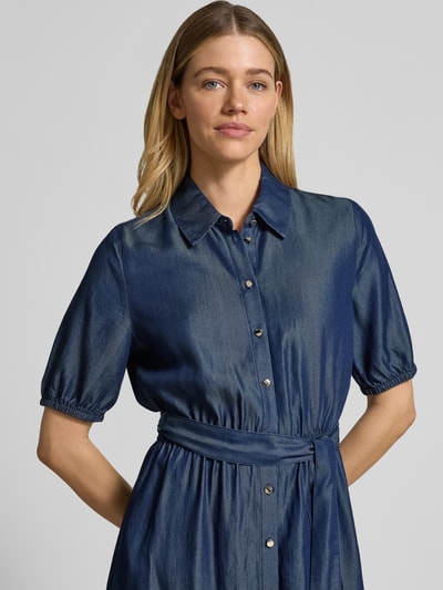 Frauenmodel trägt Tailliertes Freizeitkleid aus reinem Lyocell von s.Oliver BLACK LABEL in Denim-Optik, Kurzarm, Knopfleiste, Taillengürtel, Midi-Länge, Twill Materialverarbeitung, reine Viskose, Ganzkörperansicht von vorne.