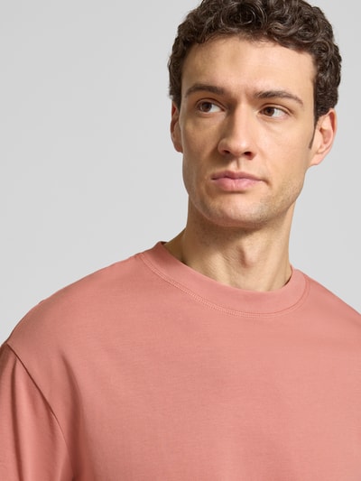 Männermodel trägt Relaxed Fit T-Shirt aus reiner Baumwolle Modell 'RELEXASPEN' von SELECTED HOMME in Altrosa, Feinripp, unifarben, Nahaufnahme Oberkörper.