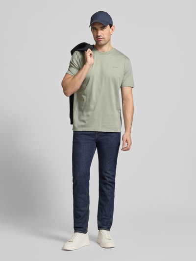 Männermodel trägt T-Shirt mit Rundhalsausschnitt von CK Calvin Klein aus Baumwoll-Mix in Regular Fit, dezentes Grün, Ganzkörperansicht von vorne.