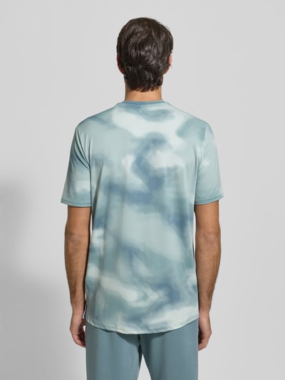 Mannelijk model draagt T-Shirt im Allover-Look mit Logo van Under Armour in lichtblauw met all-over print, regular fit, rugaanzicht, materiaalmix met stretch, ronde hals, ruglengte bij maat M 75 cm.