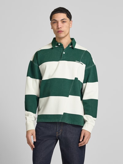 Mężczyznamodel nosi koszulkę polo Relaxed Fit Poloshirt aus reiner Baumwolle Modell 'Castelluccio' von Pegador, zielono-kremowe szerokie pasy, wyhaftowane logo, kołnierzyk polo z listwą guzikową, ściągacze na rękawach, długość tyłu w rozmiarze M: 69 cm, ganzkörperansicht von vorne.