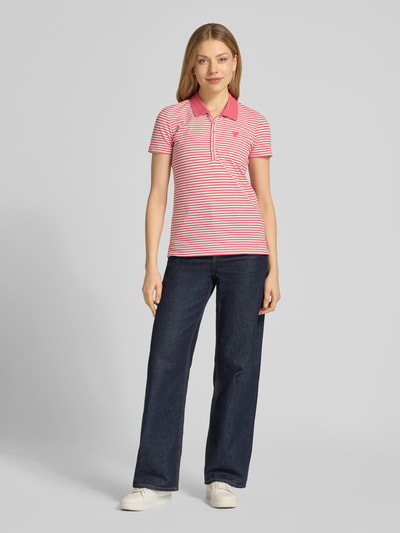 Frauenmodel trägt Regular Fit Poloshirt aus Baumwoll-Mix von Tom Tailor, Optik:Allover-Muster, gestreift, Motiv-Stitching, Dunkelblau und Rosa, Ganzkörperansicht von vorne.