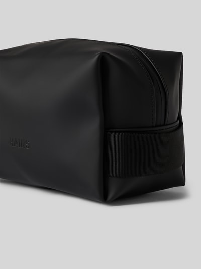 Produktfoto, schwarze Wash Bag mit Logo-Detail von Rains, rechteckige Form, glatte Oberfläche, großes Hauptfach mit Reißverschluss, seitlicher Trageriemen, Steckfach innen, Maße 20x14x11 cm, Schulterriemen 14 cm.