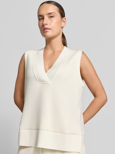 Vrouwenmodel draagt top uit mix van viscose en elastaan in tricotlook Model 'Freida' van VARLEY, kleur crème, los model, v-hals, ribboorden, ruglengte bij maat S: 40 cm, Ganzkörperansicht van voren.