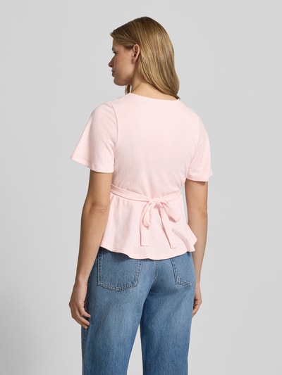 Frauenmodel trägt Regular Fit Bluse in Wickel-Optik Modell 'PELLY' von Only in zartem Rosa, strukturierter Stoff, Bindegürtel, Ganzkörperansicht Rückansicht.