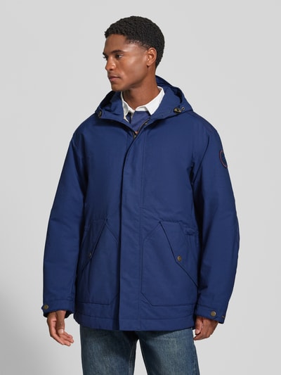 Männermodel trägt Parka mit Pattentaschen Modell 'ASKO' von Napapijri in Blau, Material-Mix, gerader Schnitt, Ganzkörperansicht von vorne.