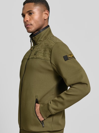 Mężczyzna nosi Sweatjacke mit Reißverschluss od PME Legend, elastyczna mieszanka bawełny, prosty krój, stójka, kieszenie na zamek, detale z logo, długość tyłu 72 cm, długość rękawa 67 cm, oliwkowy, tekstura gładka, widok z przodu, ujęcie całej sylwetki.