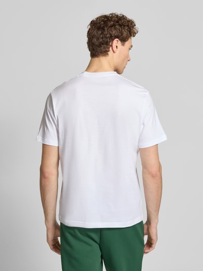 Männermodel trägt Regular Fit T-Shirt aus reiner Baumwolle von Lacoste, unifarben in Weiß, Logo-Stitching, Ganzkörperansicht Rückansicht