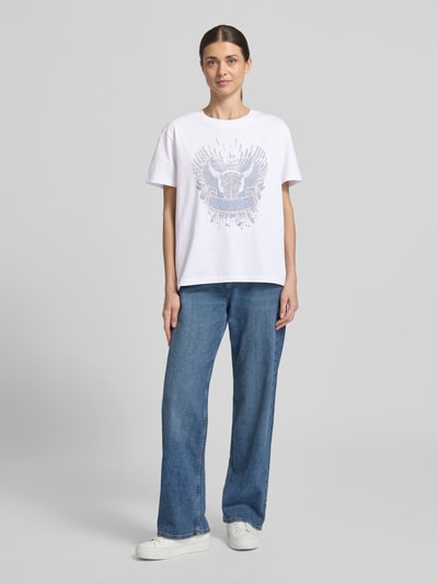 Frauenmodel trägt T-Shirt mit überschnittenen Schultern Modell 'Washa' von MOS MOSH in Weiß, Baumwolle, lockerer Schnitt, Rundhals, blaue Jeans, Ganzkörperansicht von vorne.