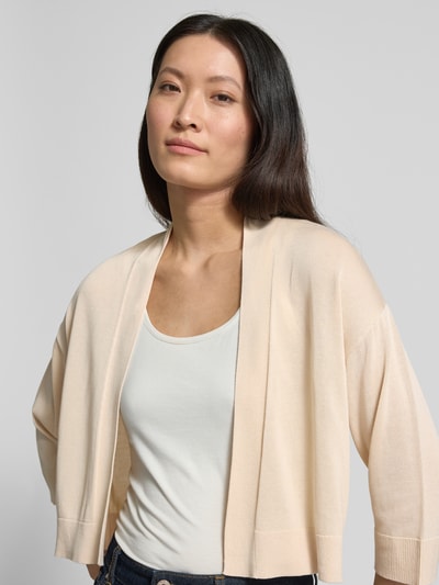 Frauenmodel trägt Strickjacke aus Lyocell-Baumwoll-Mix in offener Passform von comma, helle Farben, glatte Textur, Nahaufnahme Oberkörper. Regular Fit, 3/4-Arm, Rückenlänge 43 cm, Ärmellänge 32 cm.