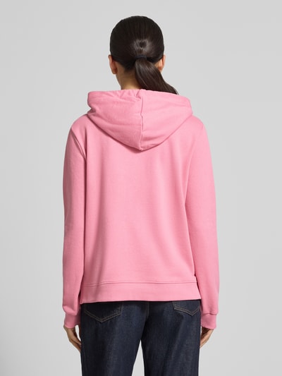 Vrouwenmodel draagt Regular Fit Hoodie aus Baumwoll-Mix van Tom Tailor Denim in effen roze sweatstof met borduursel, lange mouwen, geribde boorden, capuchon met tunnelkoord, zijsplitten, materiaalmix katoen, volledige achteraanzicht.