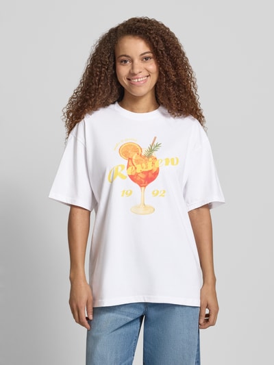 Frauenmodel trägt Damen T-Shirt mit Rückseitigem Motiv-Print von REVIEW, Oversized, Reine Baumwolle, Rundhalsausschnitt, Vorderansicht Ganzkörperansicht.