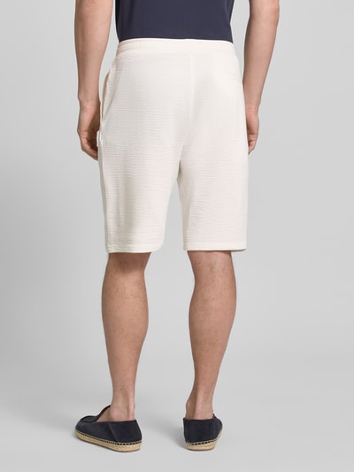 Männermodel trägt Relaxed Fit Bermudas aus Baumwoll-Mix Modell 'DETROIT' von s.Oliver RED LABEL in Creme, unifarben, Waffelstruktur, Ganzkörperansicht Rückansicht.
