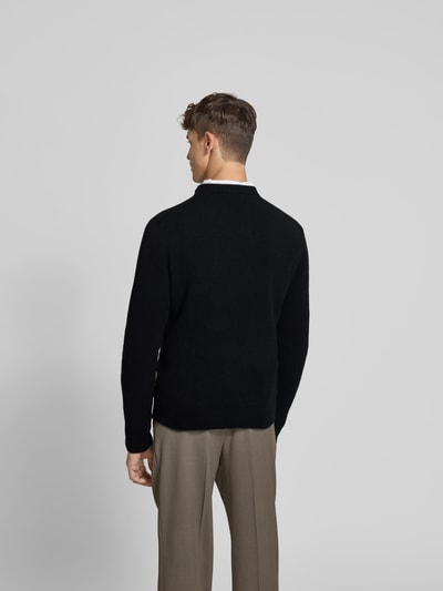 Männermodel trägt schwarzen Pullover aus Woll-Mix mit Yak-Anteil von Filippa K, Strick-Optik, Stehkragen, Rückenansicht Ganzkörperansicht.