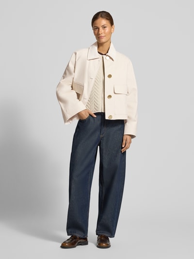 Frauenmodel trägt Jacke mit Pattentaschen von Armani Exchange im Baumwoll-Elasthan-Mix in Beige, Ganzkörperansicht von vorne. Regular Fit, Umlegekragen, Knopfleiste, große Pattentaschen, Rückenlänge 55 cm, Schulterbreite 48 cm, Brustweite 59 cm, Ärmellänge 62 cm.