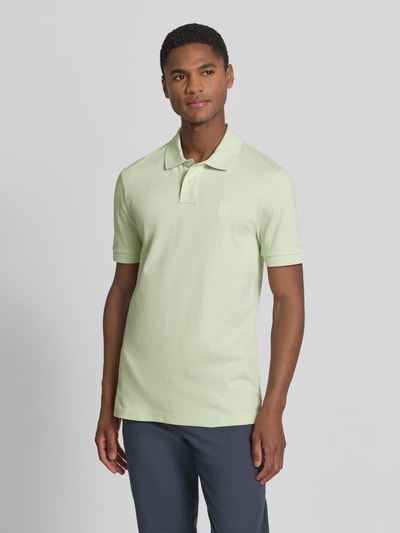 Männermodel trägt Slim Fit Poloshirt aus Baumwoll-Mix Modell 'PASSENGER' von BOSS Orange, Optik: Unifarben, Logo-Patch, Ganzkörperansicht von vorne.