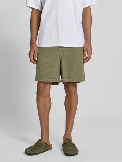 Männermodel trägt Shorts mit elastischem Bund Modell 'PADOW' von American Vintage aus Reine Baumwolle, Olive, Loose-Fit, Nahaufnahme Oberschenkel.