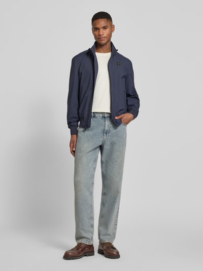 Männermodel trägt Jacke mit Label-Patches Modell 'Anson' von Blauer Usa in Dunkelblau, Reißverschlusstaschen, gerader Schnitt, Ganzkörperansicht von vorne.