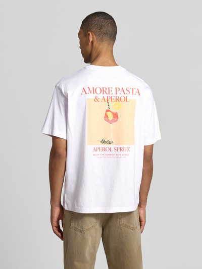 Männermodel trägt T-Shirt mit rückseitigem Motiv-Print von MCNEAL in Weiß, gerader Schnitt aus Bio-Baumwolle, Ganzkörperansicht Rückansicht.