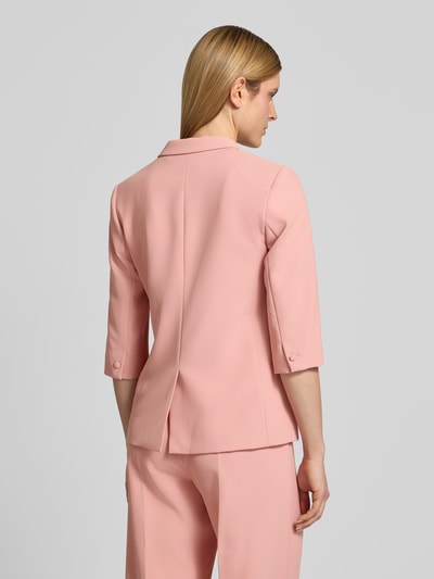 Vrouwenmodel draagt Regular Fit Blazer met 3/4-mouw model 'Junie Miley' van MOS MOSH in zachtroze met reverskraag en knoopsluiting, ruglengte maat 36: 65 cm, borstwijdte 48 cm, mouwlengte 42 cm, geheelopname achteraan.
