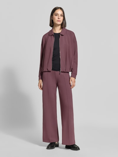 Kobiece model prezentuje Wide Fit Hose mit Ziernähten od Christian Berg Woman, elastyczna mieszanka materiałów z domieszką modalu, ozdobne szwy, elastyczny pas, cała sylwetka widoczna z przodu.