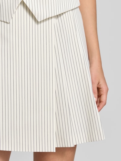 Frauenmodel trägt Leicht ausgestellter Mini-Rock in Wickeloptik Modell 'RIBERI' von HUGO mit feinen, vertikalen Streifen auf cremefarbenem Twill, Nahaufnahme Unterkörper.