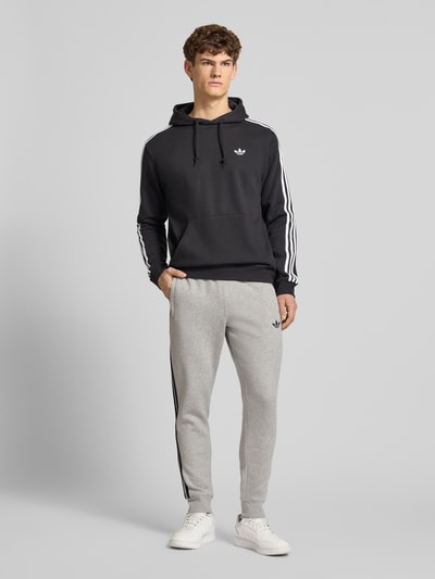Mannelijk model draagt Sweatpants mit elastischem Bund van adidas Originals in grijs, los fit, katoenmengsel, label-stitching, steekzakken, elastische tailleband, volledige lichaamsaanzicht van voren
