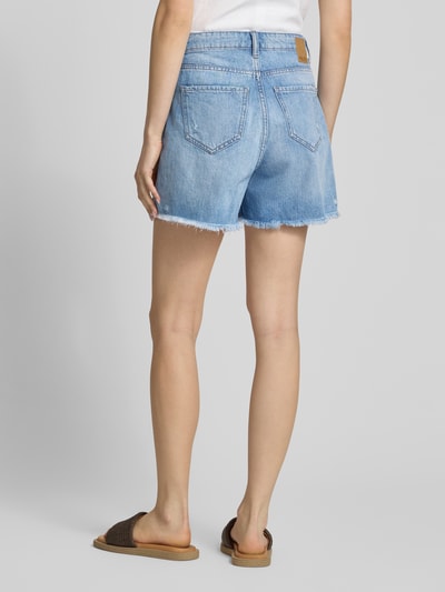 Mädchen trägt Regular Fit Jeansshorts aus reiner Baumwolle Modell 'SUMMER' von Pieces, denim, używany wygląd, krój regular fit, pięciokieszeniowy design, szlufki na pasek, guzik i ukryty zamek, łatka z logo, twill, Ganzkörperansicht Rückansicht.