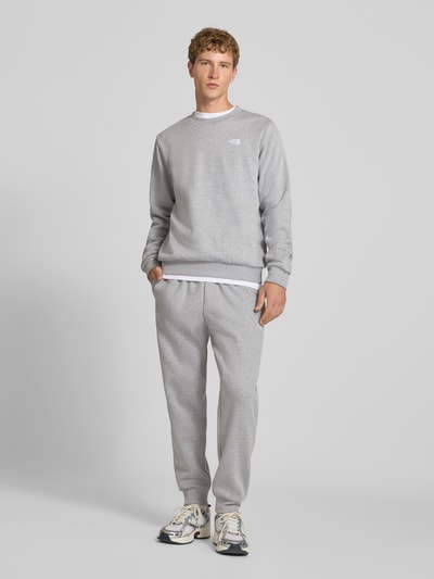 Männermodel trägt Relaxed Fit Sweatpants aus katoenmix Model 'EVOLUTION' van The North Face, Heren sweatpants, elastische band met tunnelkoord, zij-steekzakken, binnenbeenlengte bij maat M 75 cm, grijs, ganzkörperansicht van voren