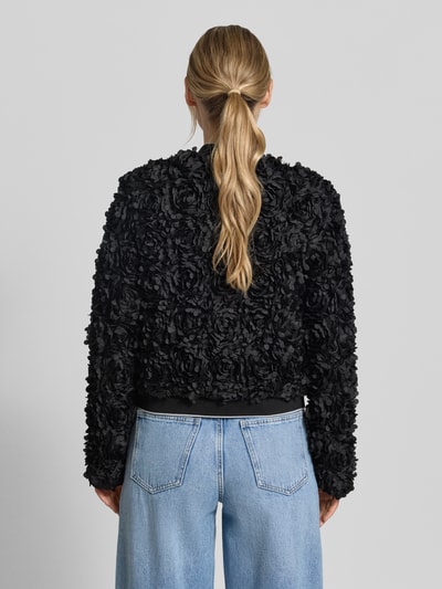 Frauenmodel trägt Blouson mit Label-Patch Modell 'JADE' von Frieda & Freddies, schwarze 3D-Blumenstruktur, Gerader-Schnitt, Gerippter Saumabschluss, Rückenlänge 53 cm, Schulterbreite 40 cm, Brustweite 50 cm, Ärmellänge 65 cm, Ganzkörperansicht Rückansicht.