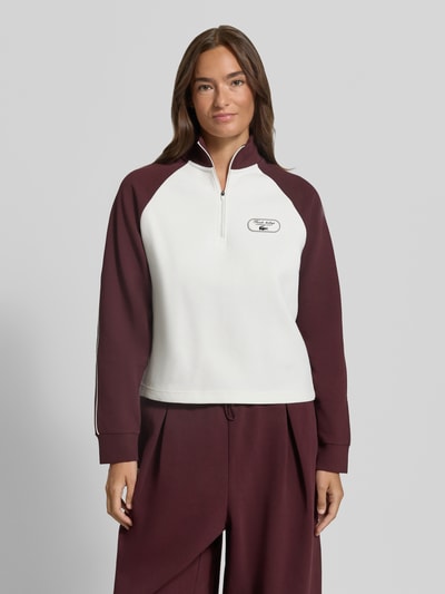 Frauenmodel trägt Regular Fit Sweatshirt aus Baumwoll-Mix von Lacoste, Two Tone in Weiß und Bordeaux, Label Patch, Reißverschlussdetail, Ganzkörperansicht von vorne