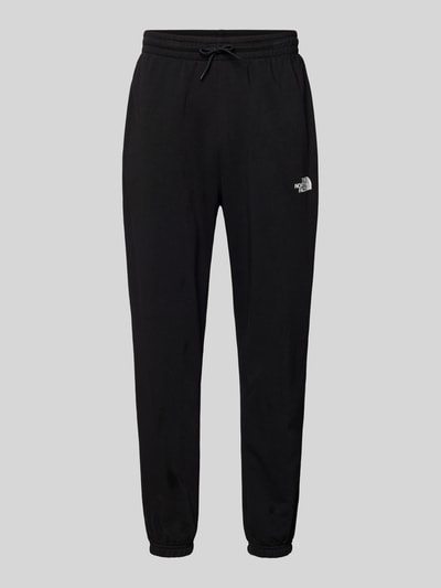 Produktfoto, Sweatpants mit Logo-Print von The North Face in Schwarz, Baumwoll-Mix, Slim-Fit, elastischer Bund mit Kordelzug, elastische Abschlüsse, Innenbeinlänge 70 cm bei Größe M, schlichtes Design mit glatter Textur.