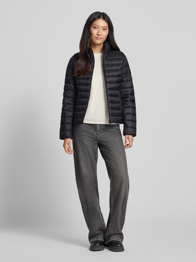 Modelka kobieca nosi czarną kurtkę pikowaną Regular Fit Steppjacke mit Stehkragen von Marc O'Polo, szerokie szare spodnie, jasny top, pełny widok sylwetki z przodu, damska kurtka pikowana od Marc O'Polo.